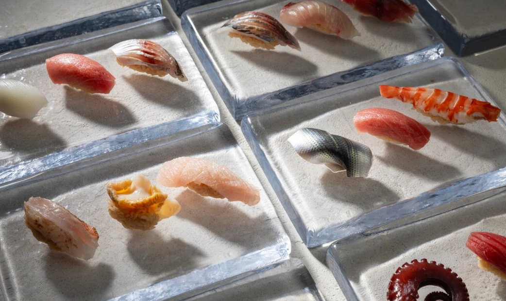 Multiple different types of sushi on clear plates