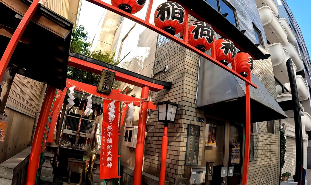 ntrance to a small Japanese shrine with red torii gates.