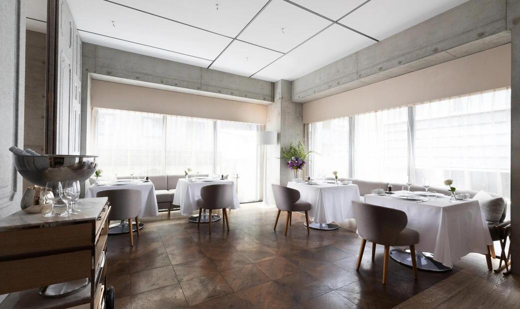 A bright restaurant with white tablecloths and large windows.