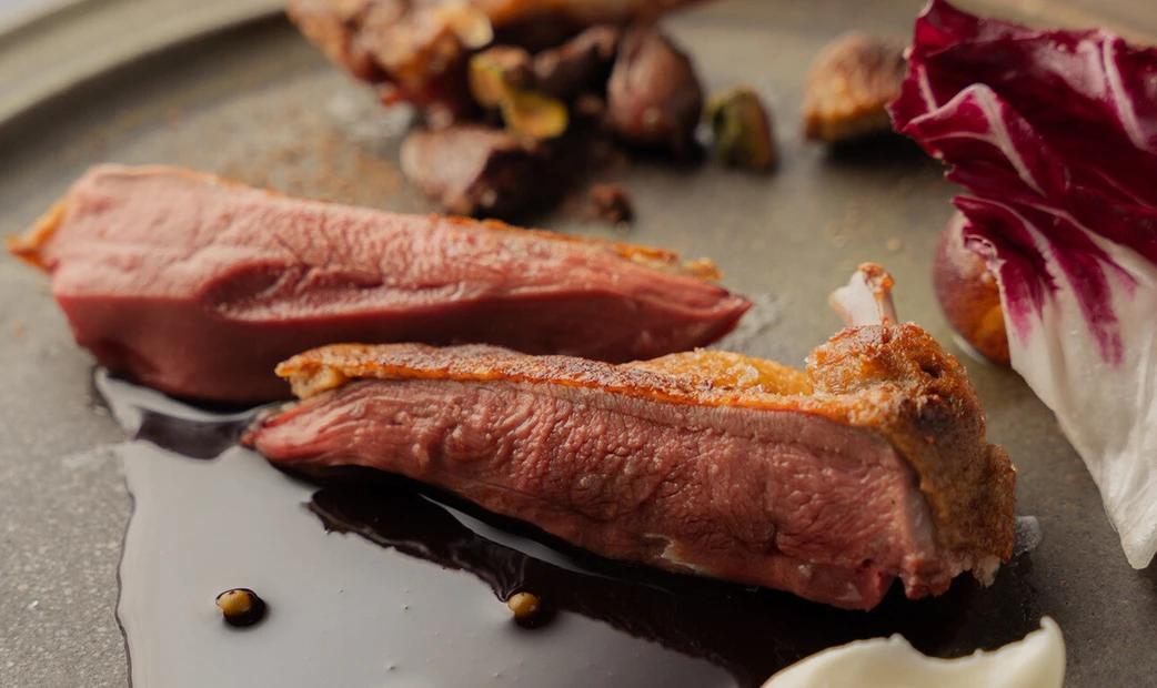 Slices of duck breast with crispy skin, served with sauce and vegetables