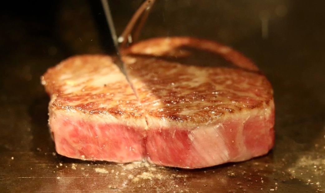 Meat being grilled on a teppan (iron plate).