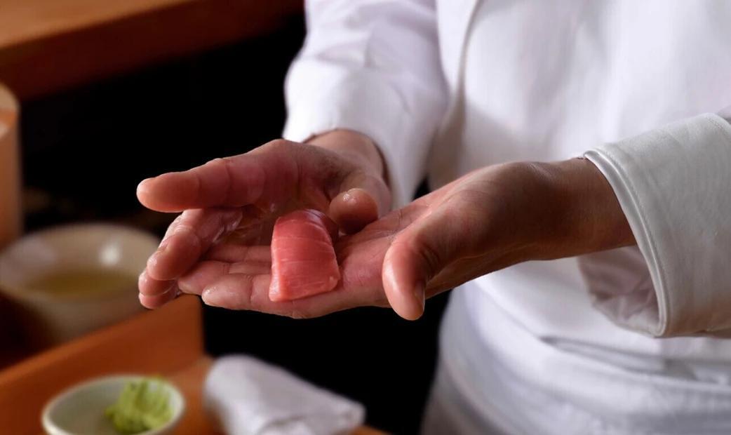 A sushi chef is holding tuna