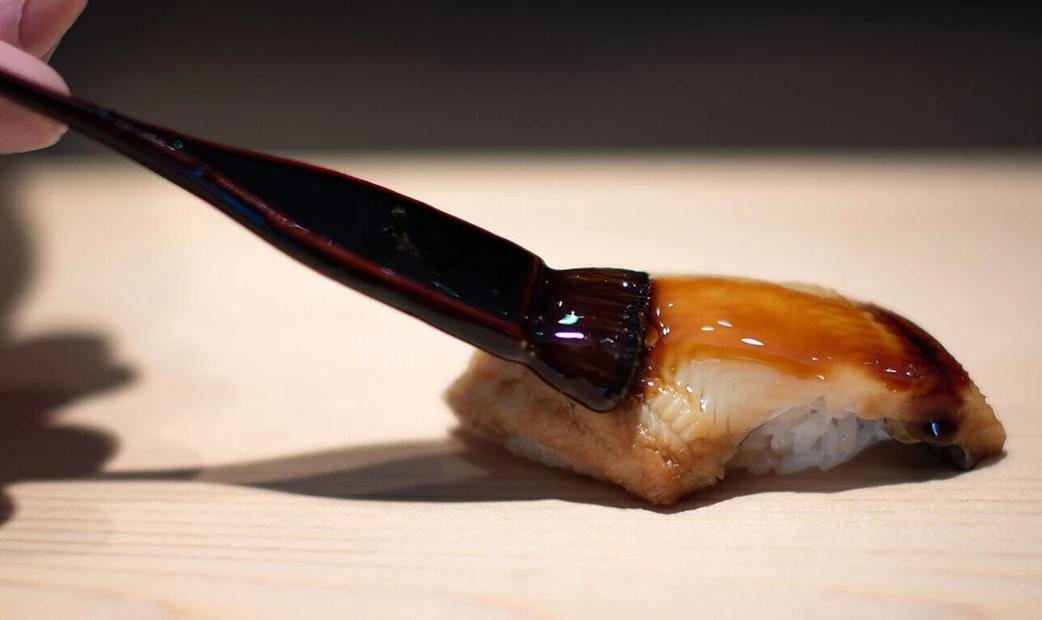 Applying sauce to conger eel sushi