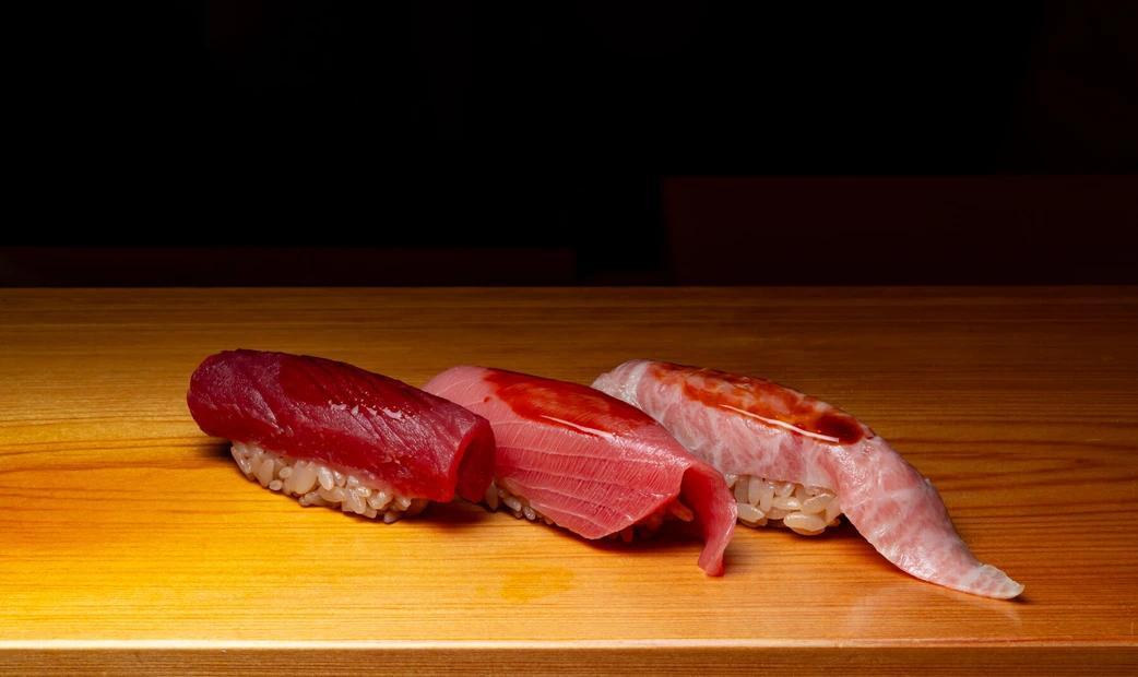 Close-up of three pieces of sushi on a wooden counter