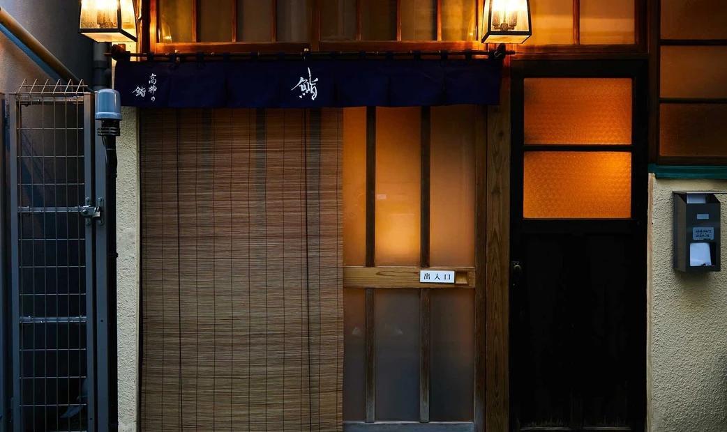 Front entrance of a traditional Japanese restaurant with a wooden door and curtain